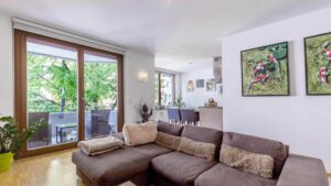 Wohnzimmer der Wohnung in Sendling mit brauner Couch, Terrassentür und Bildern an der Wand