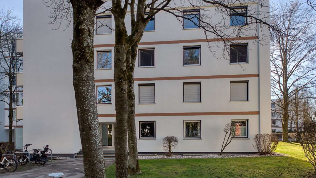 Mehrgeschossiges Wohnhaus mit Balkonen hinter kahlen Bäumen in Solln, München