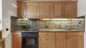 Küchenzeile mit Backofen, Granitarbeitsplatte und Mosaikfliesenspiegel in Wohnung Solln