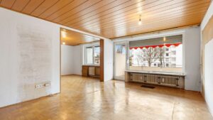 Leerer Wohn-Essbereich mit sichtbaren Wandschäden und Holzdecke, renovierungsbedürftig, Solln