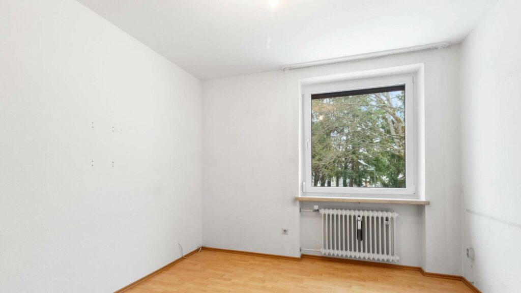 Leeres, frisch gestrichenes Zimmer mit hellem Parkett und Heizkörper unter dem Fenster in Solln