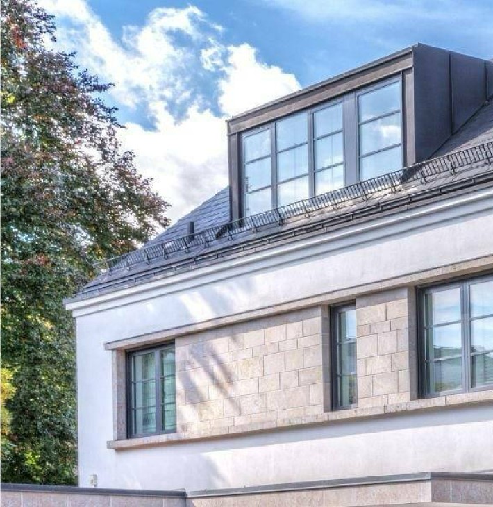 Moderne Dachgaube und Natursteinfassade eines Wohnhauses in München