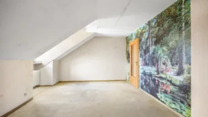 Empty attic room with slanted ceiling and decorative photo wallpaper in an apartment in Munich Berg am Laim – Rogers Immobilien