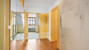 Unrenovated hallway with yellow cupboard doors and parquet flooring in an apartment in Munich-Berg am Laim – Rogers Immobilien