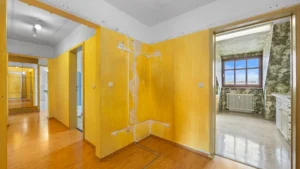 Unrenovated hallway with yellow built-in wardrobes and parquet flooring in an apartment in Munich Berg am Laim – Rogers Immobilien