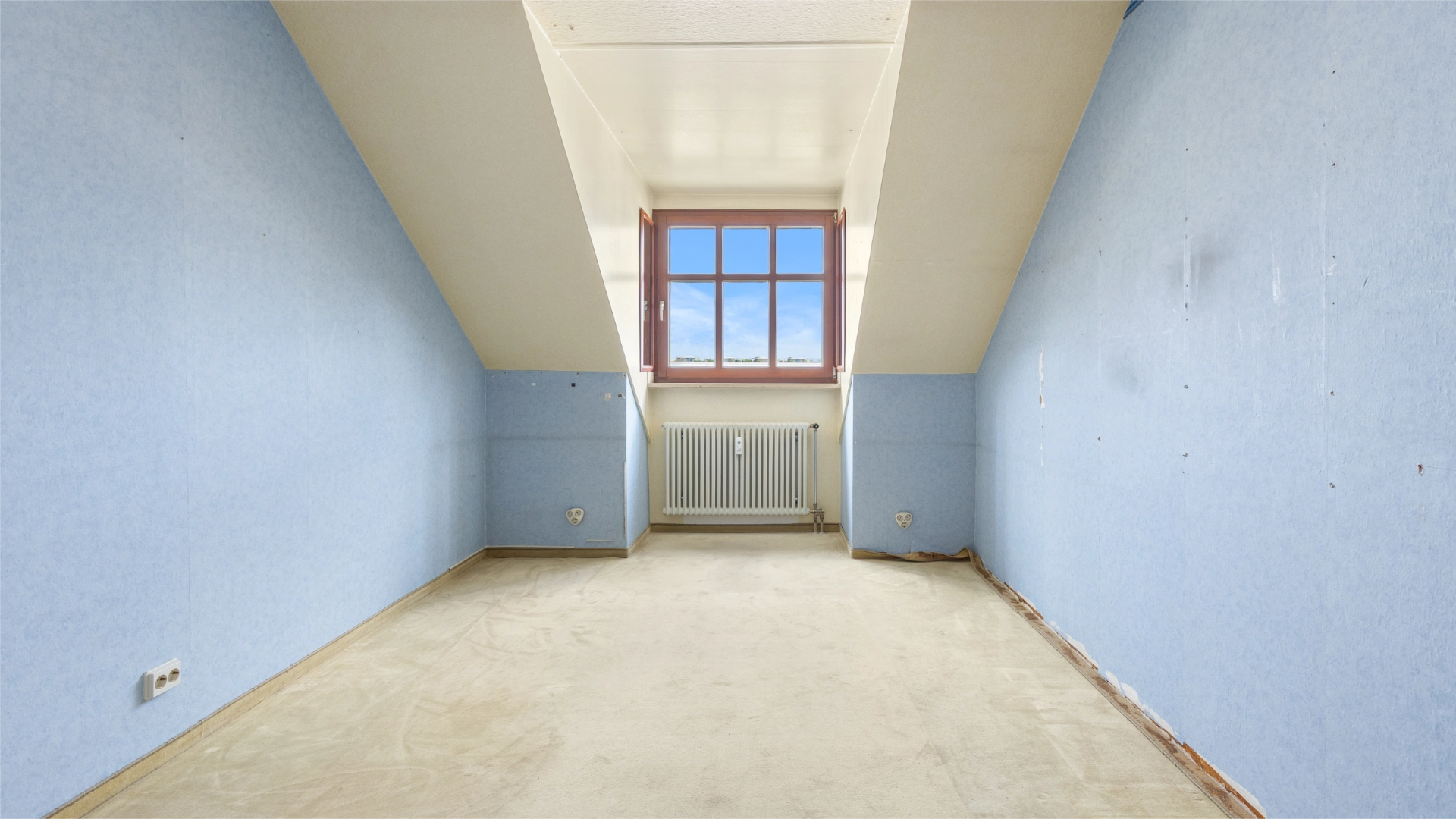 Empty unrenovated room with blue walls under the sloping roof in Munich-Berg am Laim – Rogers Immobilien