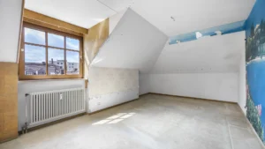 Empty unrenovated attic room with window view over the city in Munich Berg am Laim – Rogers Immobilien