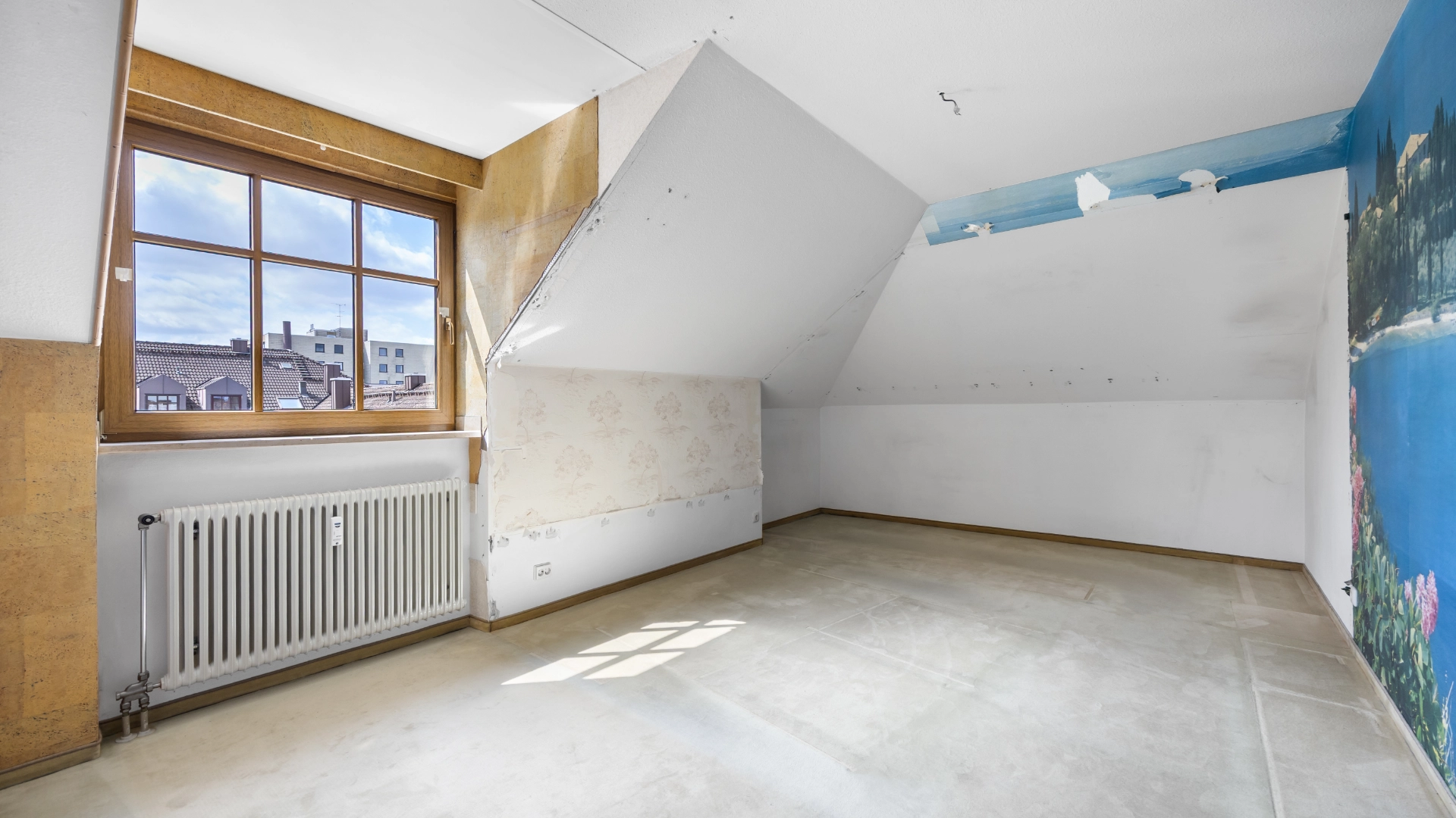 Empty unrenovated attic room with window view over the city in Munich Berg am Laim – Rogers Immobilien