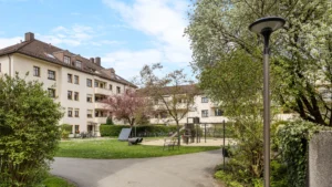 Green space with a playground and bench in the inner courtyard of the residential complex in Munich-Berg am Laim – Rogers Immobilien