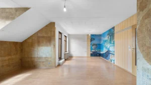 Unrenovated living area with wooden flooring, wood panelling, and wallpaper in Munich Berg am Laim – Rogers Immobilien