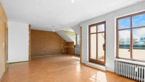 Empty unrenovated living space with wooden floor and patio door in Munich-Berg am Laim – Rogers Immobilien