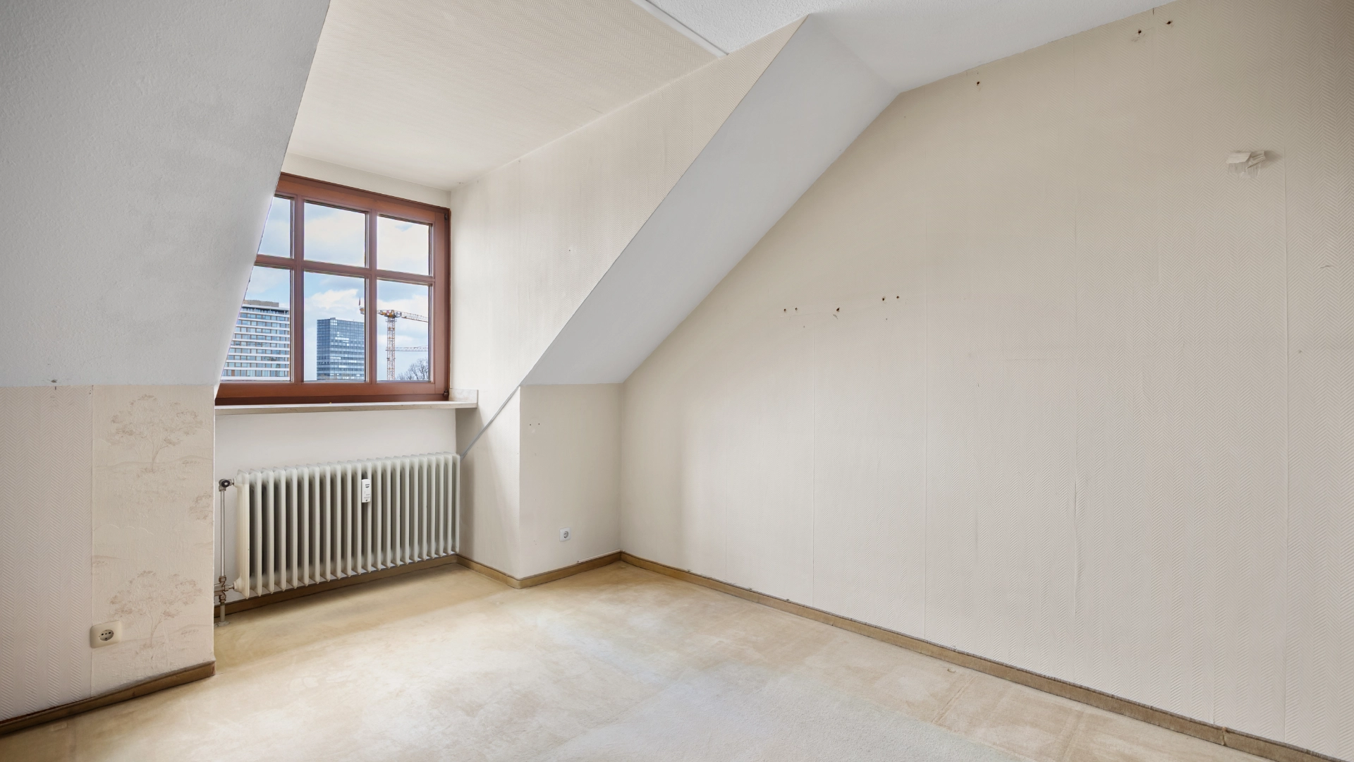 Empty plain room under the sloping roof before renovation in Munich-Berg am Laim – Rogers Immobilien