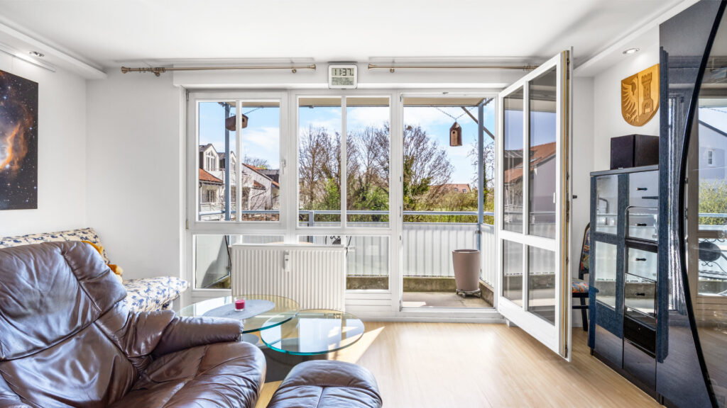 Existing living room with leather sofa and patio door before renovation in Munich-Feldmoching – Rogers Immobilien