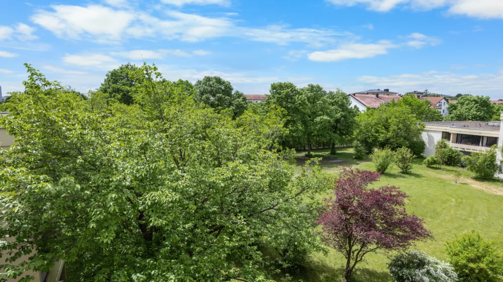 Blick vom Balkon über Baumkronen und Grünfläche zur Nachbarbebauung in München-Forstenried