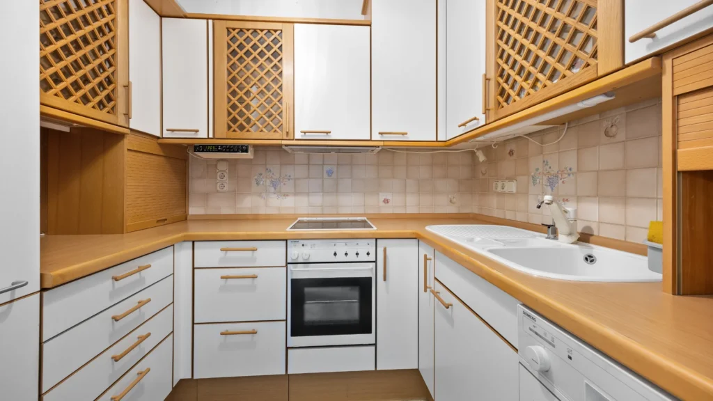 Bestehende Einbauküche mit Holzfronten und hellen Fronten in der Wohnung in München-Forstenried