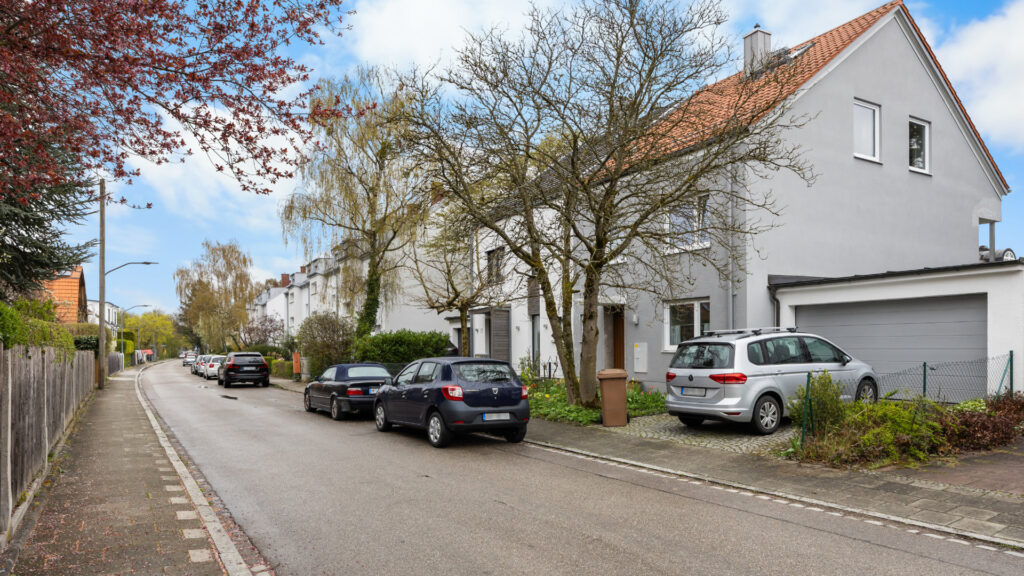 Rear view of the semi-detached house in Munich-Obermenzing with a balcony, terrace, and large garden full of blossoms