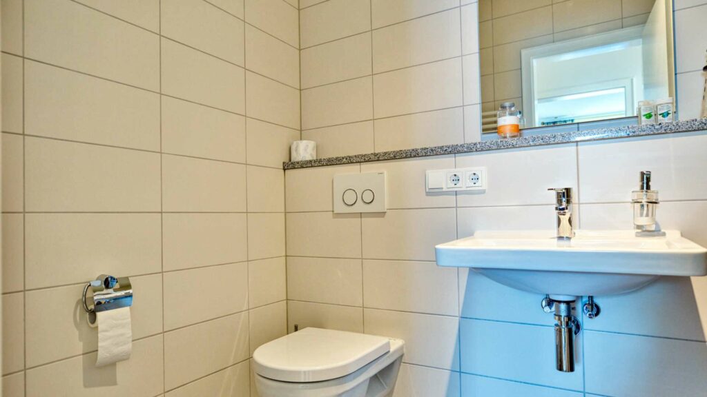 Tiled guest toilet with sink and toilet in a house in Munich-Obermenzing – Rogers Immobilien
