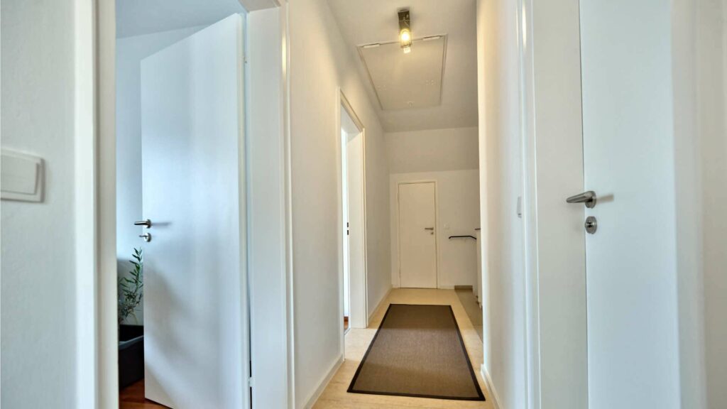 Bright hallway with multiple doors and a runner in a house in Munich-Obermenzing – Rogers Immobilien
