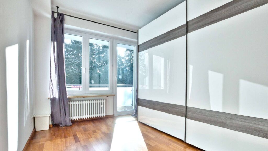 Empty room with built-in wardrobe and parquet flooring in a house in Munich-Obermenzing – Rogers Immobilien