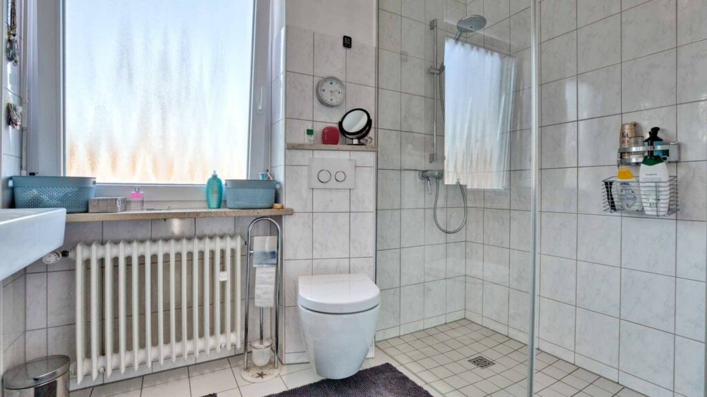 Tiled bathroom with shower enclosure and toilet in a house in Munich-Obermenzing – Rogers Immobilien