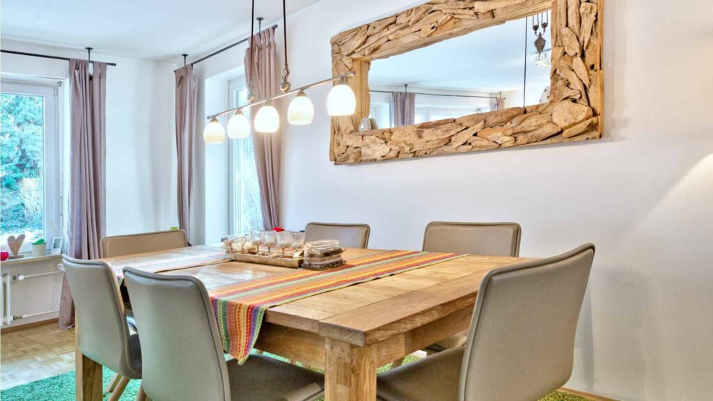 Dining area with a wooden table and a large driftwood mirror in a house in Munich-Obermenzing – Rogers Immobilien
