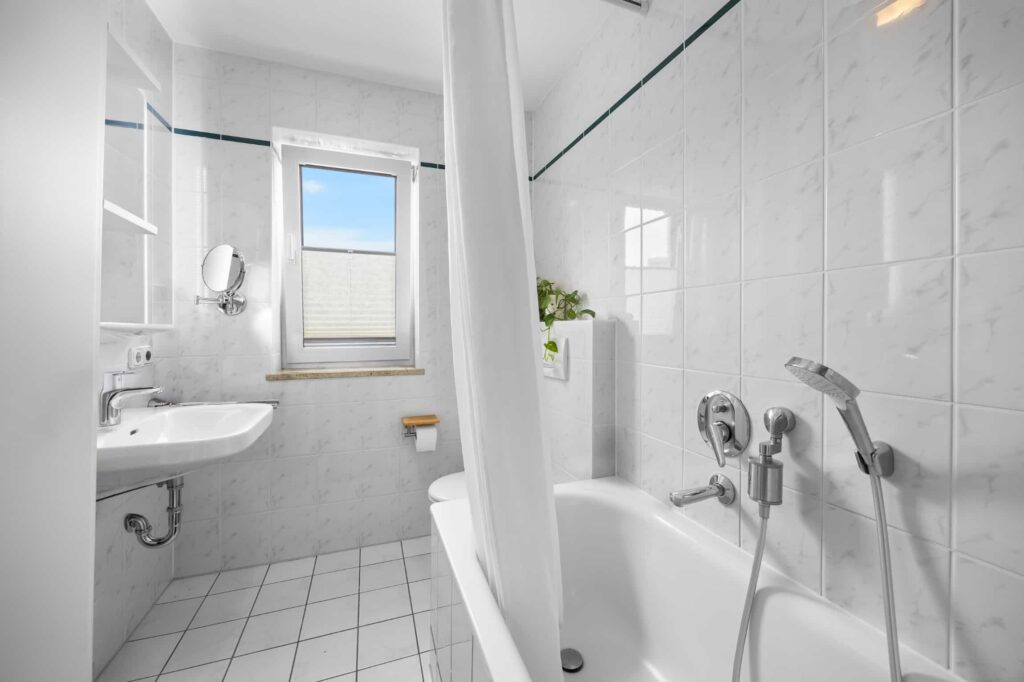 Gefliestes Badezimmer mit Tageslichtfenster, Badewanne und Dusche