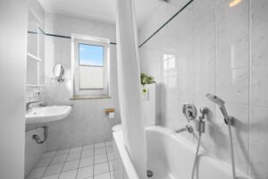 Gefliestes Badezimmer mit Tageslichtfenster, Badewanne und Dusche