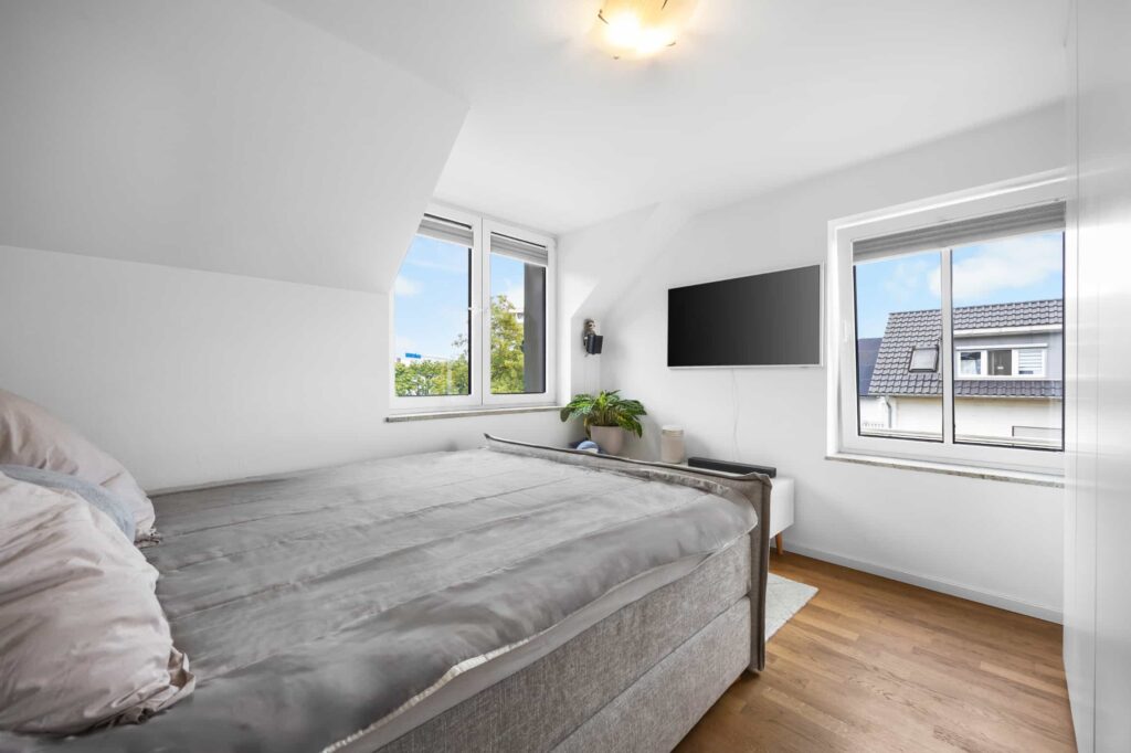 Schlafzimmer mit Dachschräge, Doppelbett und zwei Fenstern