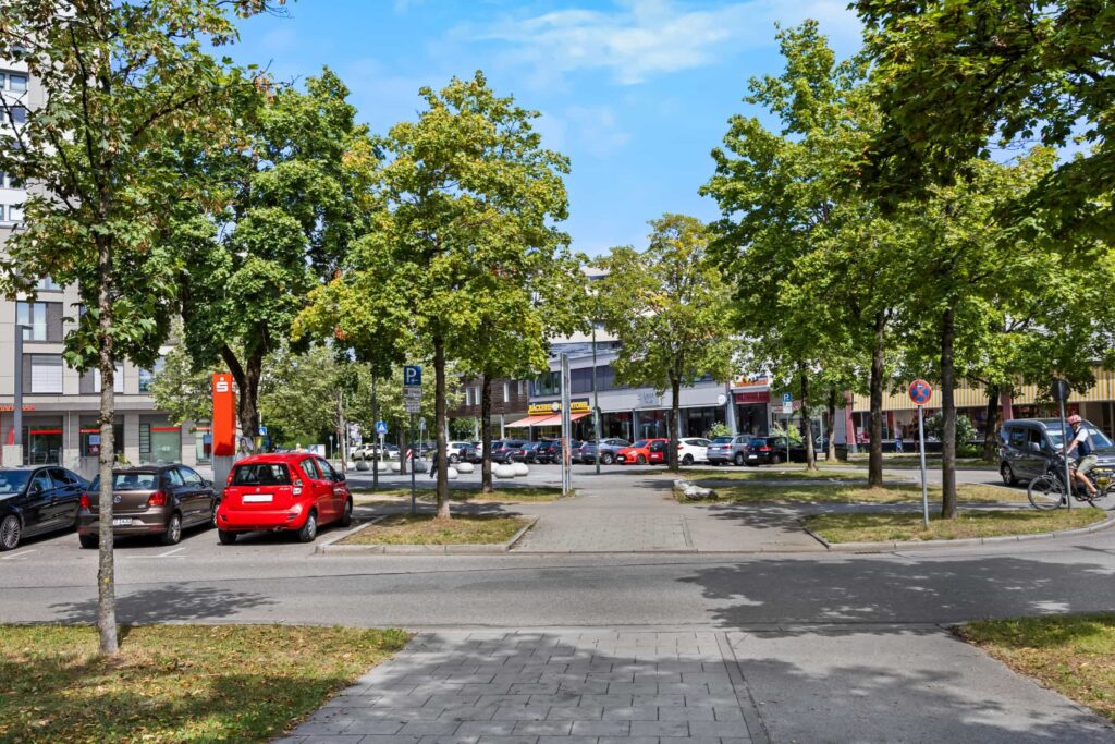 Platz mit Bäumen und Geschäften in der Nähe der Wohnung