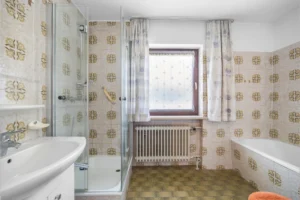 Badezimmer im Originalzustand mit Badewanne, Dusche und Fenster