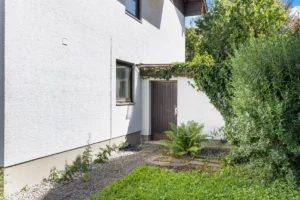 Seitlicher Grundstückszugang mit Nebeneingang und Bepflanzung