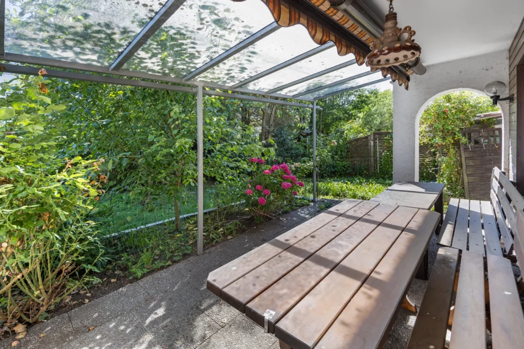 Covered terrace area with a bench and a view of the garden
