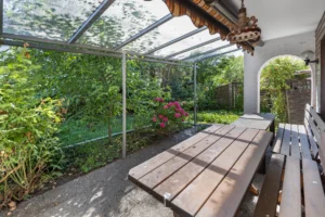 Überdachter Terrassenbereich mit Sitzbank und Blick in den Garten