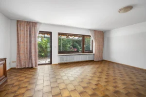 Weiträumiges Wohnzimmer mit großer Fensterfront und Terrassentür