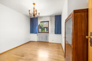 Unmöbliertes Zimmer mit Parkettboden und Blick ins Grüne